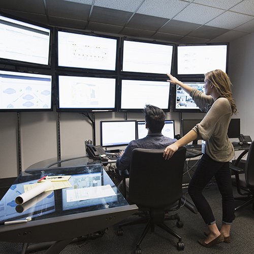 man-and-woman-working-in-control-center-with-monitors.jpg